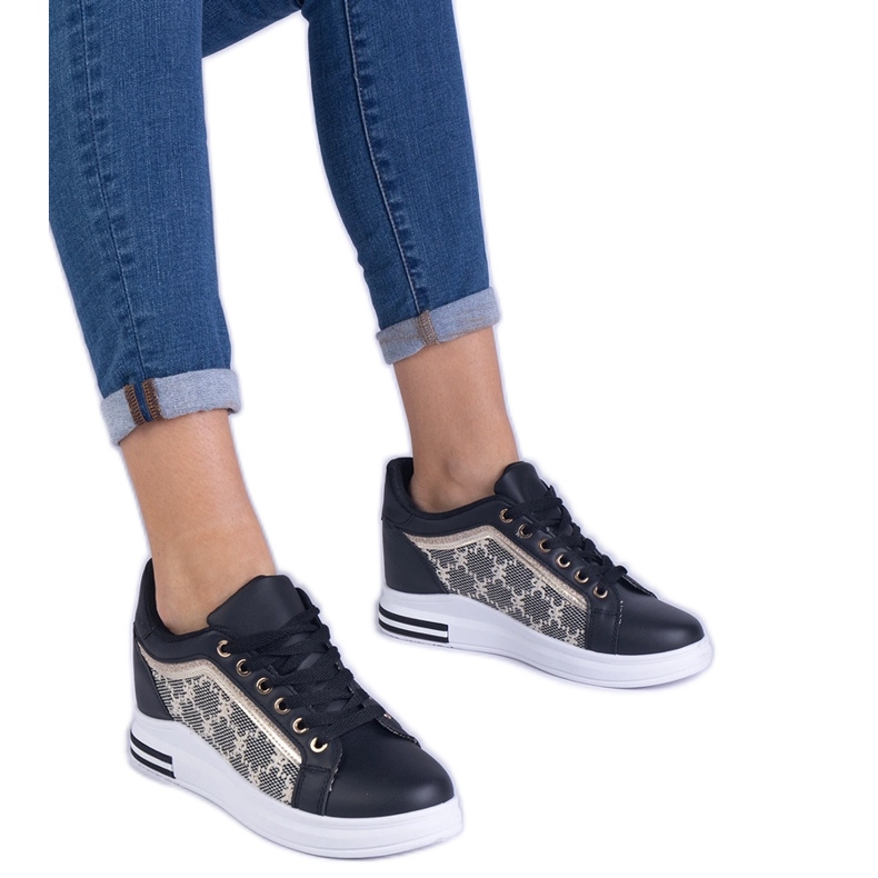 Sneaker da donna nera su un cuneo nascosto nero