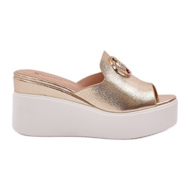 Pantofole sulla piattaforma e zeppe con un ornamento dorato d'oro