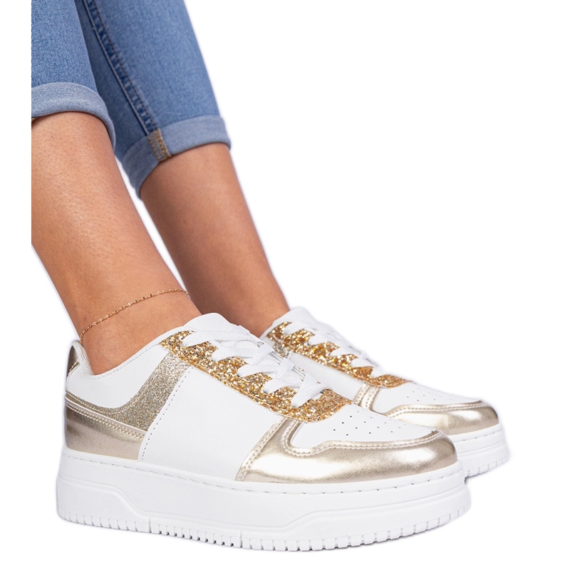Sneaker da donna dorata su una suola spessa decorata con glitter d'oro
