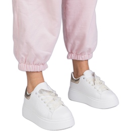 Sneaker bianche con un inserto dorato e un perno di zircone bianca