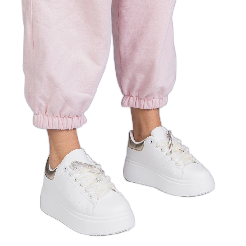 Sneaker bianche con un inserto dorato e un perno di zircone bianca