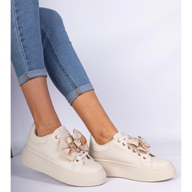 Sneaker beige decorate con un arco e un orsacchiotto dorato 1